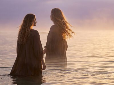 Why are Pisces so mysterious and hard to read — woman standing in shallow ocean water at dusk, soft mist around her, dreamy and ethereal mood